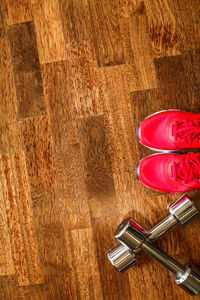 High angle view of pink shoes by dumbells on hardwood floor