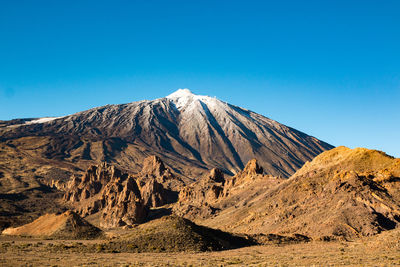 Scenic view of volcanic mountain against clear blue sky