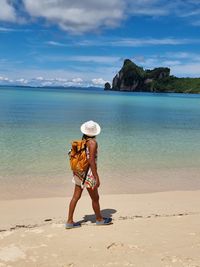 Rear view of woman walking at beach against sky