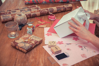 High angle view of woman hands making gift box on table