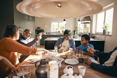 Multigenerational family enjoying together while having food on dining table at home