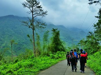 People walking on road against mountains