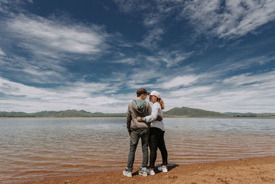 Couple standing with arm around by lake