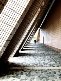 Man walking on footpath amidst buildings in city