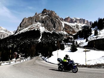 Man riding bicycle on snowcapped mountain against sky