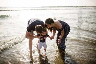 Mid 30's parents playing in ocean with infant son