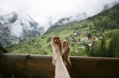 Low section of woman relaxing in balcony against mountains