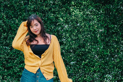 Portrait of young woman standing against plants