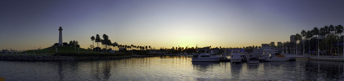 Boats moored at harbor against sky during sunset