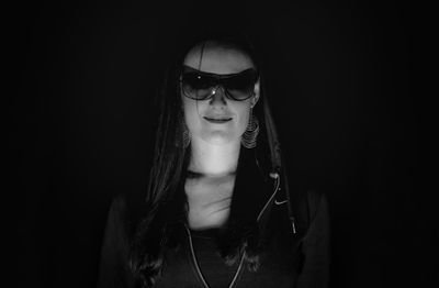 Portrait of woman wearing sunglass against black background