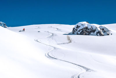 Skier skiing in fresh powder with only one track next to rock