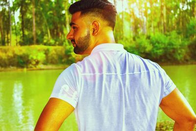 Man looking away while standing by lake