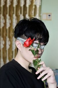 Close-up of boy with covered eyes holding rose