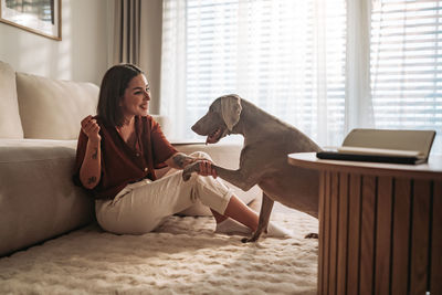 Young woman using laptop while sitting on sofa at home