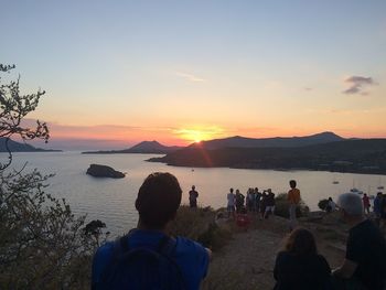 People photographing lake at sunset