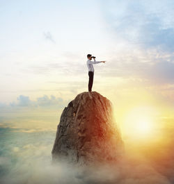 Man standing on rock against sky