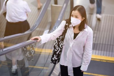 High angle view of woman standing on escalator