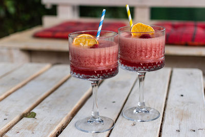 Close-up of two red cocktails in vintage glasses on white pallet table in bar