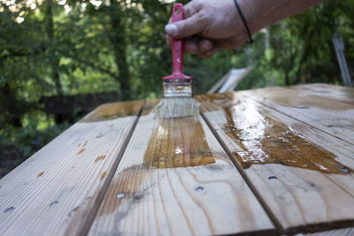 Close-up of hand holding wooden plank on table