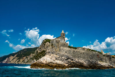 Castle by sea against blue sky