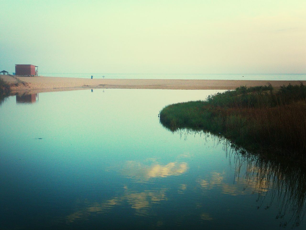 water, reflection, clear sky, tranquility, tranquil scene, copy space, waterfront, scenics, beauty in nature, sea, nature, lake, calm, standing water, sky, built structure, horizon over water, idyllic, outdoors, architecture