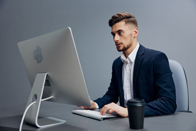 Portrait of young man using laptop at office