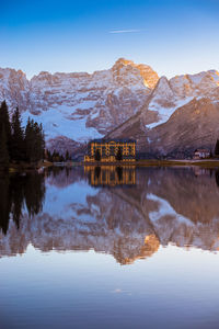 Reflection of house in lake against snowcapped mountain