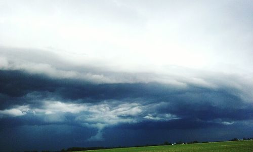 Storm clouds over field against sky