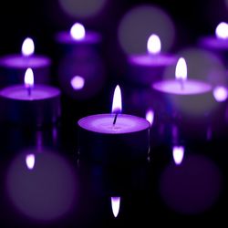 Close-up of lit tea light candle in dark room