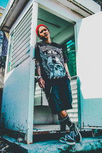 Full length portrait of young man standing against building