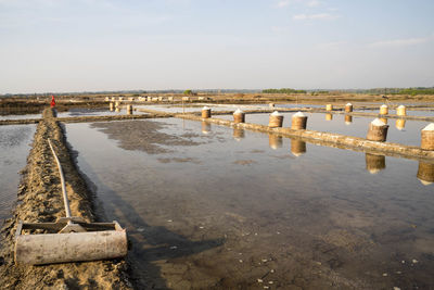 Wooden posts in sea against sky