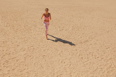 Full length of woman walking on sand at beach
