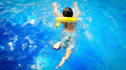 High angle view of shirtless boy swimming in pool