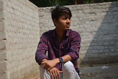 Young man looking away against wall