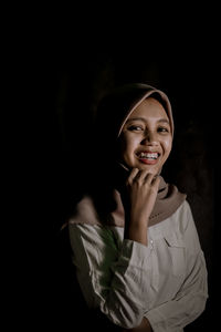 Portrait of a smiling young woman against black background