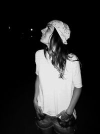 Woman looking up while standing outdoors at night