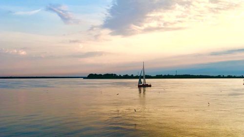 Sailboat in sea against sky during sunset