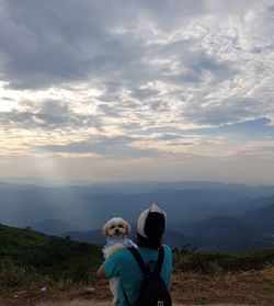 Rear view of dog on landscape against sky during sunset