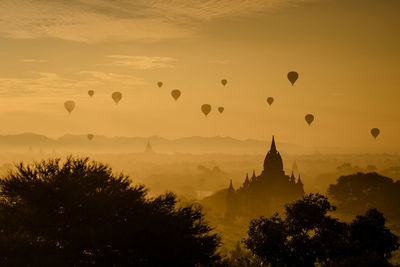 Silhouette of hot air balloons against sky during sunset