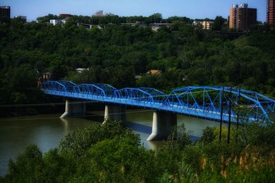Blue bridge over river amidst trees