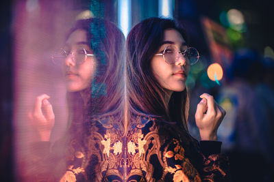 Portrait of young woman by window with reflection