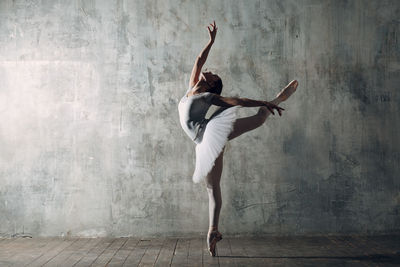 Woman dancing against gray wall
