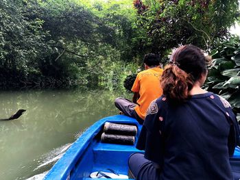 Rear view of men sitting on boat against lake