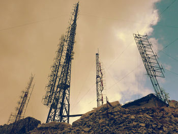 Low angle view of communications tower against cloudy sky