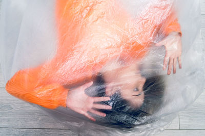 Teenage girl wrapped in plastic on floor