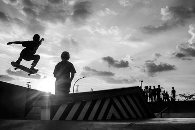 Low angle view of boy skateboarding at skateboard park against sky on sunny day