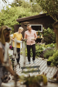 Father and son walking with bowl and plate in back yard during social event