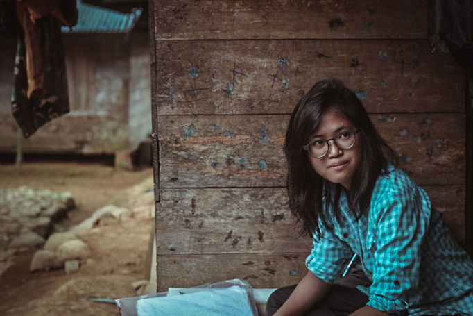 PORTRAIT OF YOUNG WOMAN SITTING AGAINST WALL