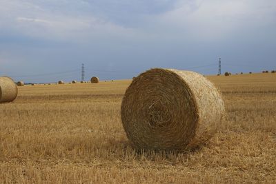 Hay bales on field against sky
