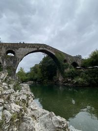 Arch bridge over river against sky